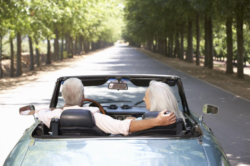 Elderly couple driving around in a convertible