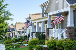 American Flags hang from the front porch of a row of upscale Victorian-style homes in celebration of the upcoming holiday. Taken in the Summer in North Carolina, with beautiful morning sunlight to celebrate, Fourth of July, Labor Day, Memorial Day or Veteran's Day. Perfect image for any Summer project.