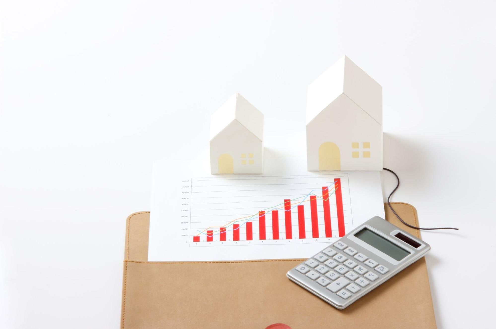 Paper houses and a calculator on top of a financial report