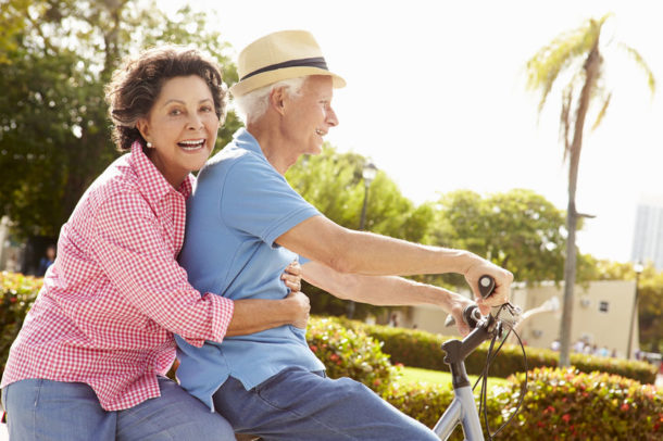 Elderly couple riding a bicycle together.