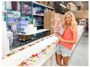 Julie Friedman holding her daughter in her business' warehouse.