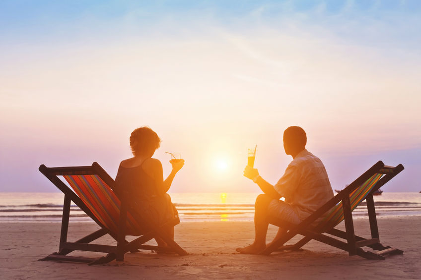 A couple drinks champagne on the beach at sunset.