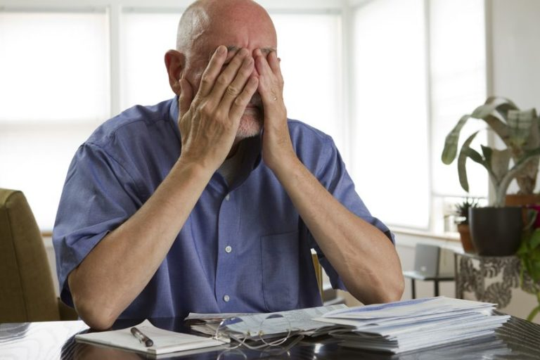 Image of stressed elderly man with hands over face.