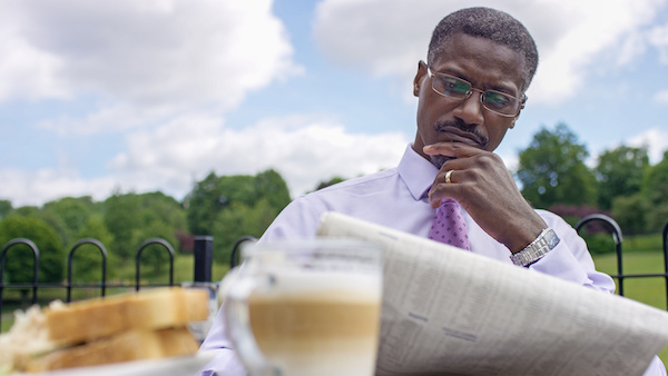 Man seriously reading the paper while having breakfast