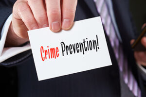 A businessman holding a business card with the words,  Crime Prevention, written on it.