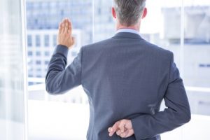 Businessman making a oath while crossing fingers behind his back