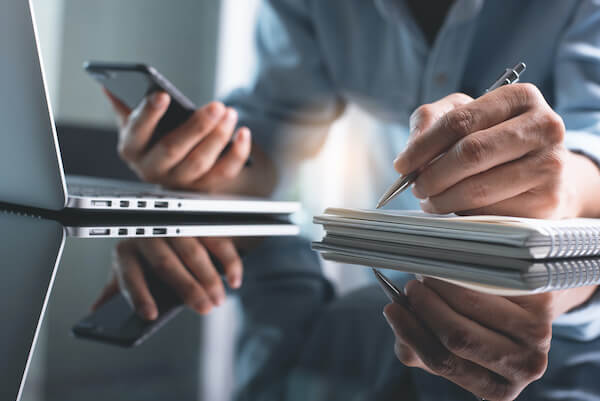 Dividend yield ratio: person checking their phone, laptop and notes