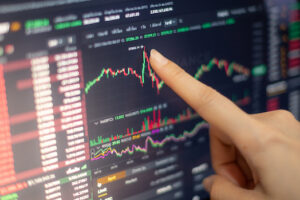 The business woman investor trading or stock brokers having a planning and analyzing with display screen and pointing on the data presented and deal on a stock exchange.