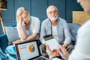 Senior couple with sad emotions during the meeting with financial consultant, signing some agreement in the office