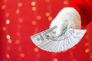Santa holding US dollar bills on a shiny light red background
