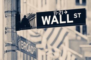 Vintage looking Wall street sign  in New York City with out of focus buildings and american flags on the background