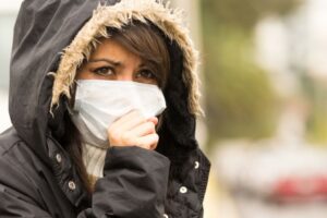 portrait of young girl walking wearing jacket and a mask in the city street concept of  pollution